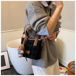 Detail of vintage quilted bucket bag with brown leather trim and cute teddy bear charm
