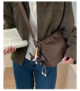 Detailaufnahme der braunen Vintage-Umhängetasche aus Leder mit Hundeanhänger und Quaste