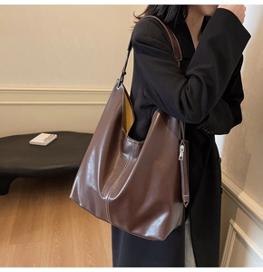 Détail du sac cabas en cuir marron foncé avec surpiqûres blanches sur l'épaule