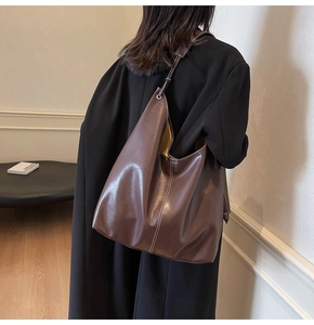 Détail d'un sac cabas en cuir marron avec surpiqûres blanches et texture lisse brillante