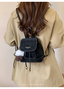 Dettaglio mini zaino nero vintage con marchio dorato e cuciture bianche a contrasto