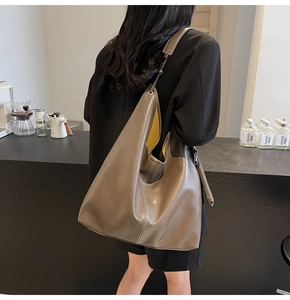 Détail du sac hobo taupe avec doublure jaune présenté dans un café chaleureux