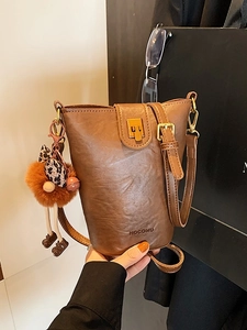 Vintage brown leather bucket bag with leopard print bow and plush ball charm accessory
