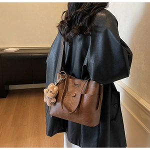 Close-up of brown vintage leather bucket bag with fashion bag embossing and a bear charm