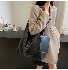 Détail d'un sac cabas en cuir noir avec surpiqûres blanches et une pochette assortie