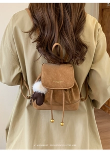 Dettaglio mini zaino vintage in pelle marrone con coulisse e ciondolo su modella
