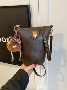 Retro coffee brown leather bucket bag with gold hardware and plush bear charm