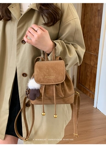 Dettaglio mini zaino retrò in pelle scamosciata marrone con logo oro e charm morbido