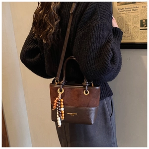 Detail of vintage patchwork bucket bag with suede texture and decorative beaded charm