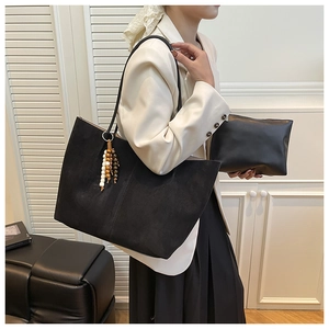 Detail view of large black matte suede tote bag with matching inner pouch and beaded charm