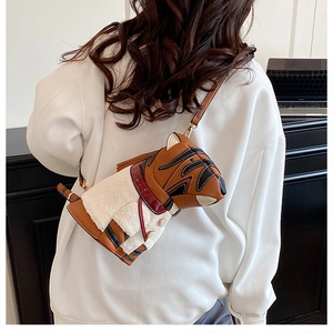 Detail of the bull terrier dog-shaped crossbody bag worn by a model in casual white hoodie