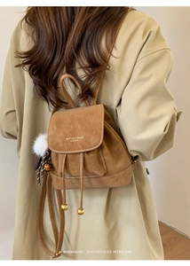 Dettaglio di zaino vintage in pelle marrone con coulisse e ciondolo a forma di peluche