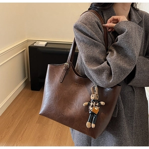 Detail of vintage brown tote bag with leather texture and cute plush rabbit charm