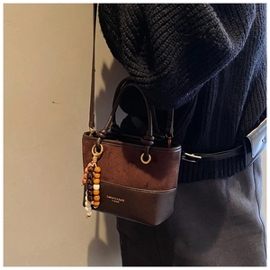 Detail of vintage patchwork bucket bag in brown suede with wooden bead tassel charm