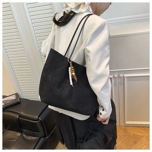 Black matte leather tote bag with unique beaded tassel detail for daily commute