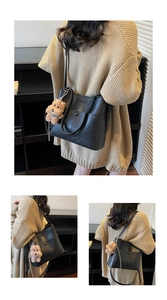 Close-up of black PU leather bucket bag with metallic button and plush puppy charm detail