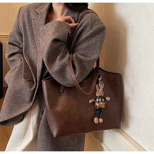 Detailed view of the dark brown retro leather tote bag with a plush bunny charm