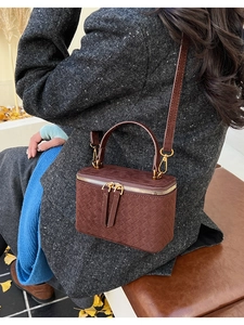 Detailed back view of a brown suede box bag with woven texture on a model's coat