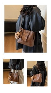 Close-up of brown textured leather commute bag with fashion lettering and bear pendant