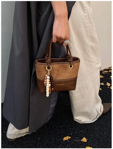 Detail of a brown patchwork bucket bag with vintage beads and suede texture