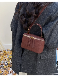 Detailed close-up of brown woven texture mini box bag on model in autumn coat