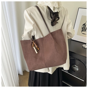 Detail of dark brown faux suede tote bag featuring unique multi-colored wooden bead tassel