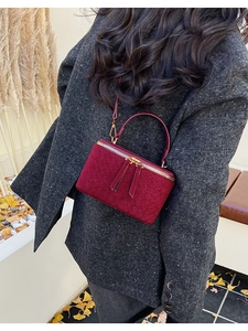 Burgundy mini box bag with gold double zipper and woven texture in an autumn setting