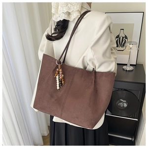 Detail view of deep brown suede tote bag featuring bohemian beaded tassel and dual straps