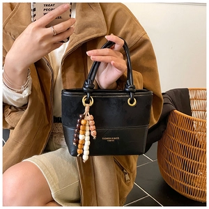 Close-up of black patchwork bucket bag with beaded tassels and minimalist brand print