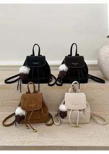 Dettaglio di quattro mini zaini in pelle scamosciata nera, marrone e beige su scale di pietra