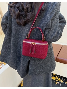Close-up of wine red suede box bag with woven texture worn with a grey winter coat