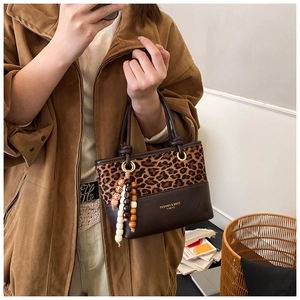 Detail of leopard print patchwork bucket bag with beaded accessory and text engraving