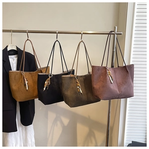 Detail of four matte suede tote bags in various colors with retro wooden bead tassels