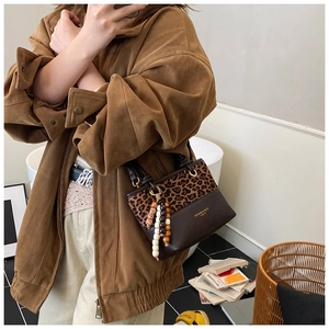 Detail of leopard print patchwork bucket bag with wooden bead strap and leather texture