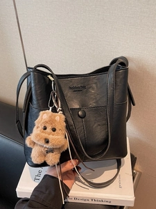 Large black leather bucket bag with shoulder strap and cute plush puppy charm