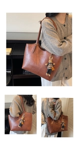 Detail of a large brown leather tote bag with a cute rabbit charm and gold lettering