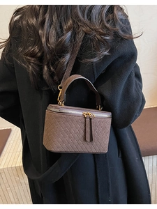 Detail of dark brown woven box bag with vintage handle and metal chain shoulder strap