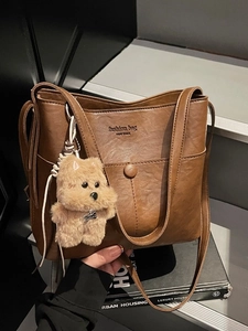 Deep brown vintage leather hobo bag with plush dog charm and stylish buckle detail