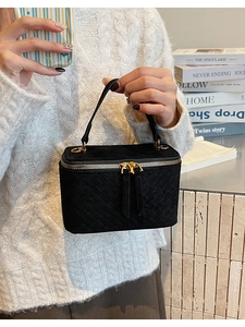 Close-up of black quilted suede mini bag with gold hardware and dual zipper closure