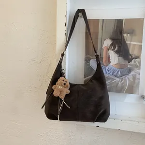 Détail du sac Hobo marron foncé avec un pendentif ours en peluche et bandoulière réglable