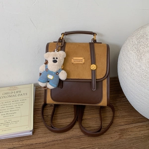 Detail of vintage contrast color backpack in caramel suede with a cute bear keychain