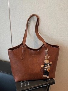 Vintage brown leather tote bag with a decorative rabbit charm for casual daily commute