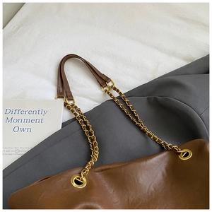 Detail of dark brown leather tote bag with metal chain strap and pebble texture finish