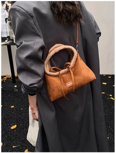 Detail of a brown suede tote bag with faux fur trim and bow decoration for winter