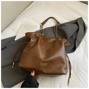 Detail of a brown leather tote with gold chain strap and stylish drawstring elements