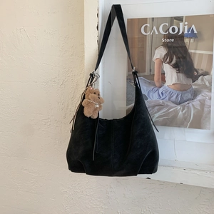 Détail du sac hobo en daim noir avec pendentif ours et décor de collier de perles