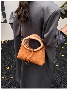 Close-up of brown suede tote bag with cream shearling trim and bow detail on a grey coat