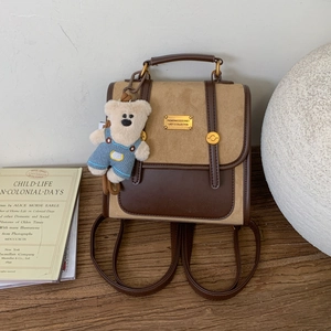 Detail of college style mini backpack with brown leather trim and blue plush bear charm