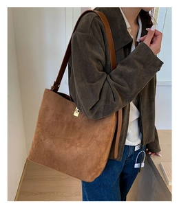 Detail of suede bucket tote bag with gold swivel lock and brown leather strap
