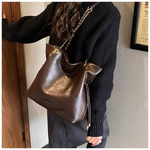 Detail of dark brown hobo tote bag featuring a gold metal chain strap and PU leather texture
